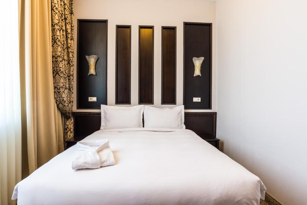 ein Schlafzimmer mit einem großen Bett mit weißer Bettwäsche in der Unterkunft Royal Petrol Hotel in Taldyqorghan