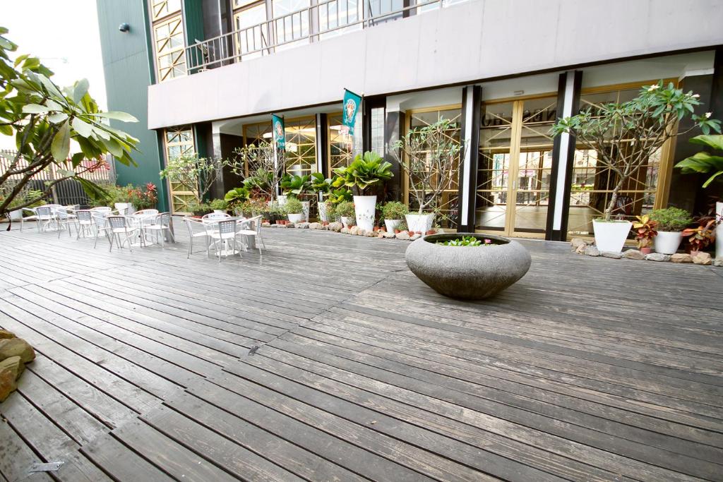 a wooden deck with chairs and a planter in front of a building at Kindness Hotel-Qixian in Kaohsiung