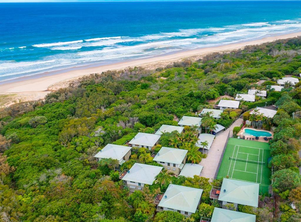 una vista aerea su una spiaggia con case e un campo da tennis di The Retreat Beach Houses a Peregian Beach