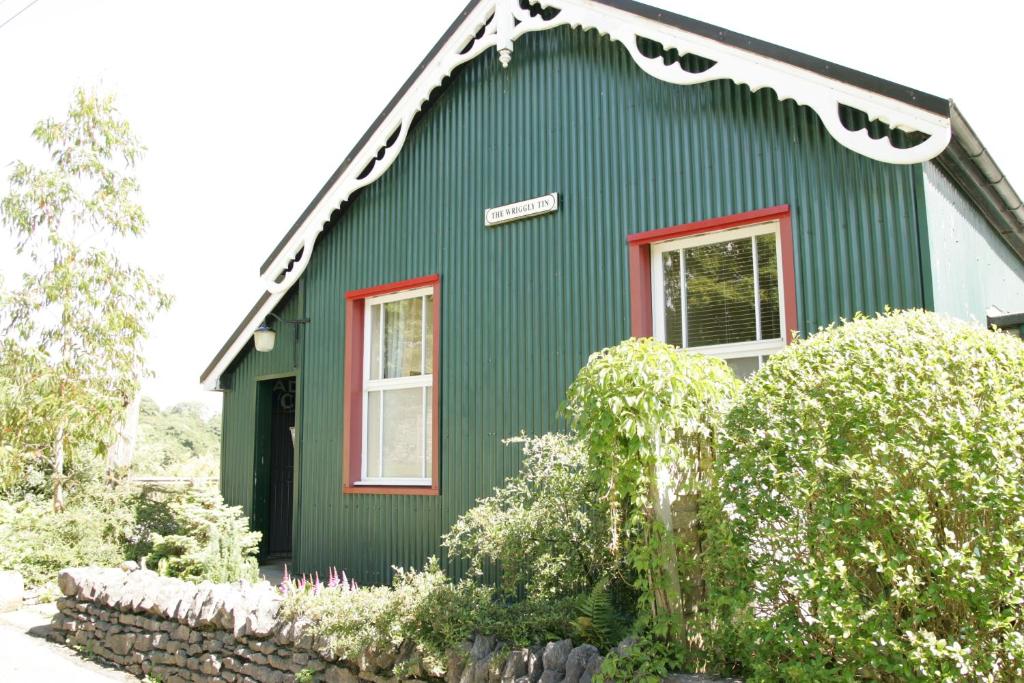 a green house with a red window at The Wriggly Tin, Millers Dale in Buxton