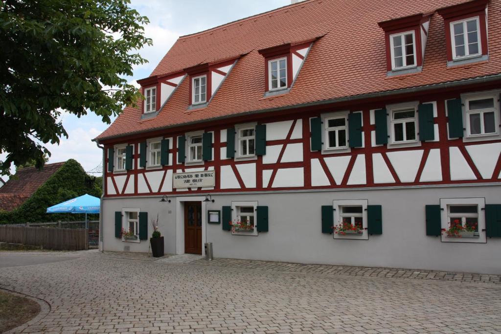 a white and red building with a red roof at Wirtshaus am Markt in Markt Nordheim