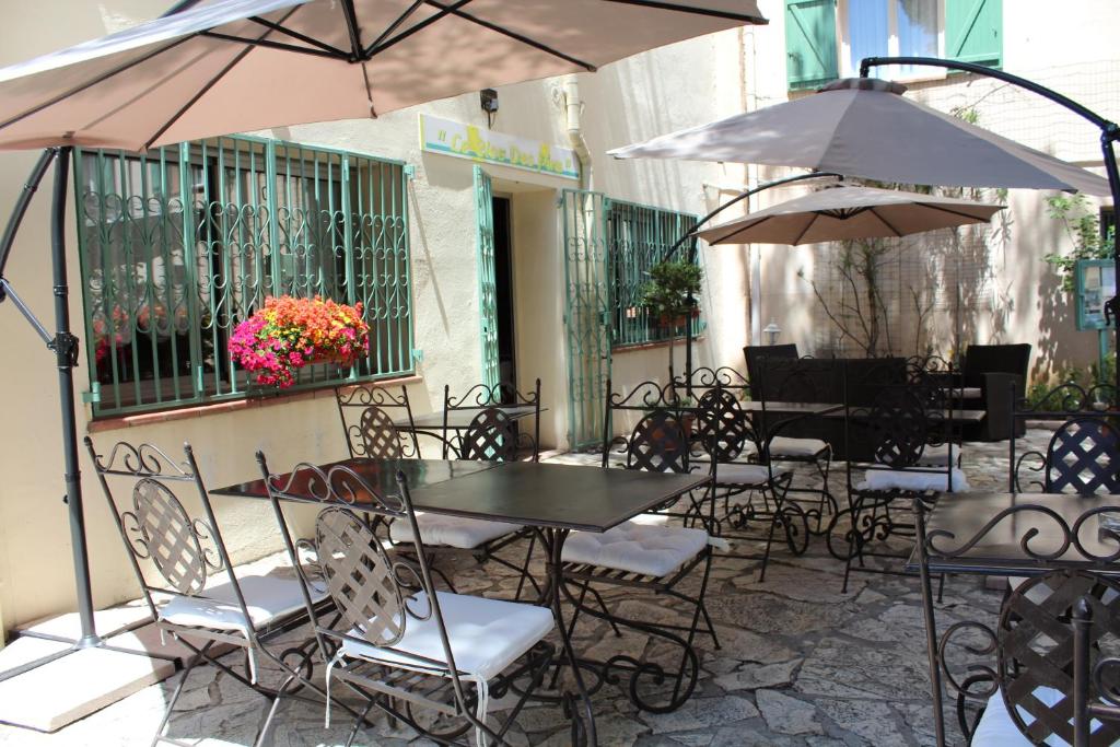 an outdoor patio with tables and chairs and umbrellas at Hôtel Le Clos des Pins in Six-Fours-les-Plages