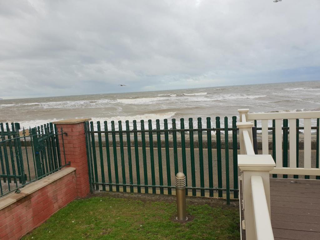 a fence on the beach with the ocean at Park Home at Golden Sands Holiday Park in Foryd