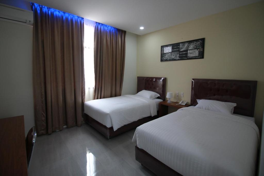 a hotel room with two beds and a window at Grand Mahoni Hotel in Banda Aceh