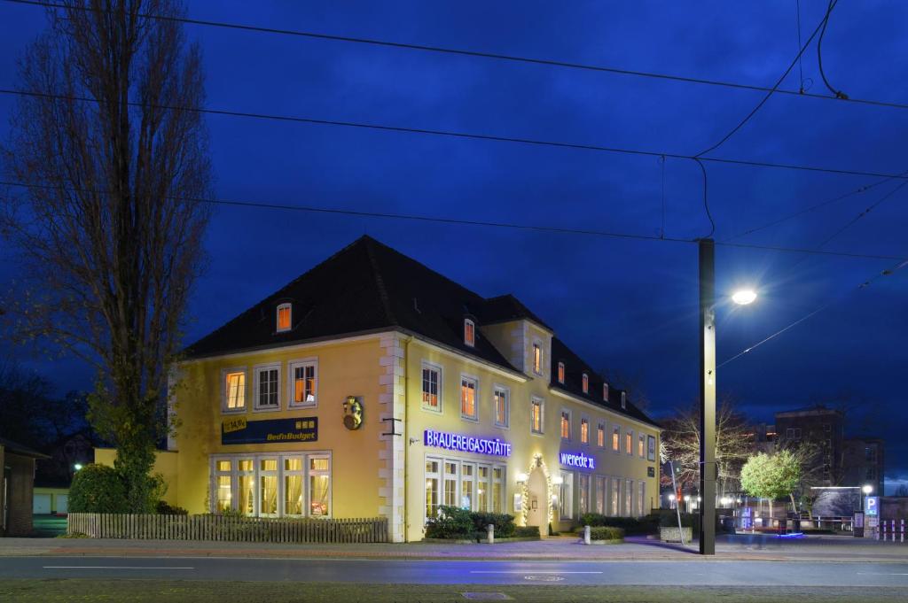 un edificio amarillo con techo negro por la noche en Bed’nBudget Expo-Hostel Dorms, en Hannover