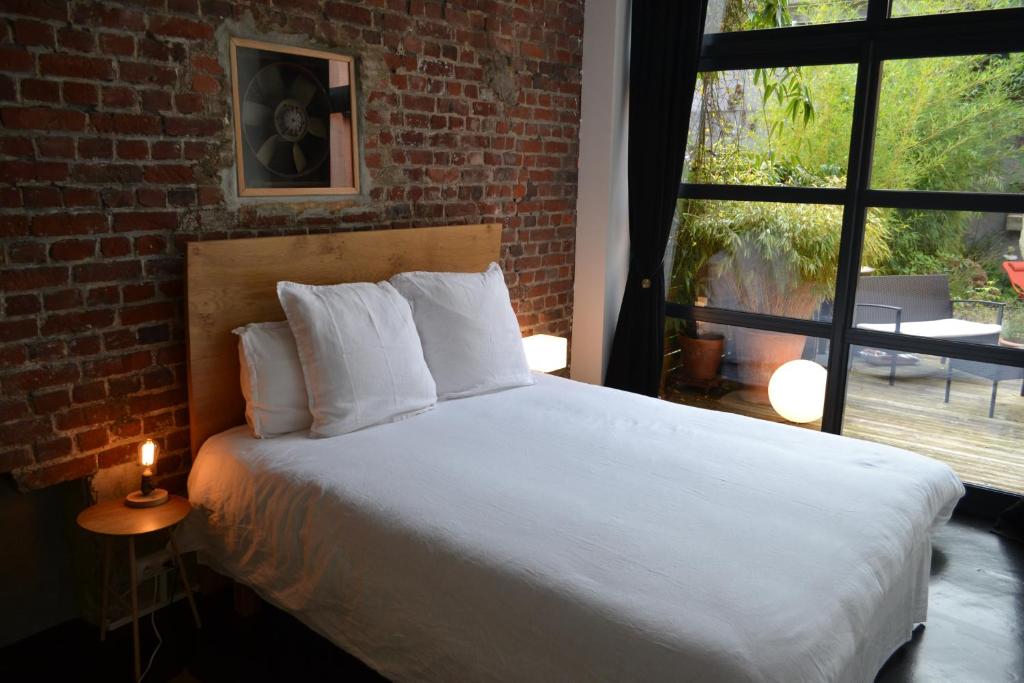 a bedroom with a bed and a brick wall at Chambre d'hôtes la Teinturerie in Roubaix