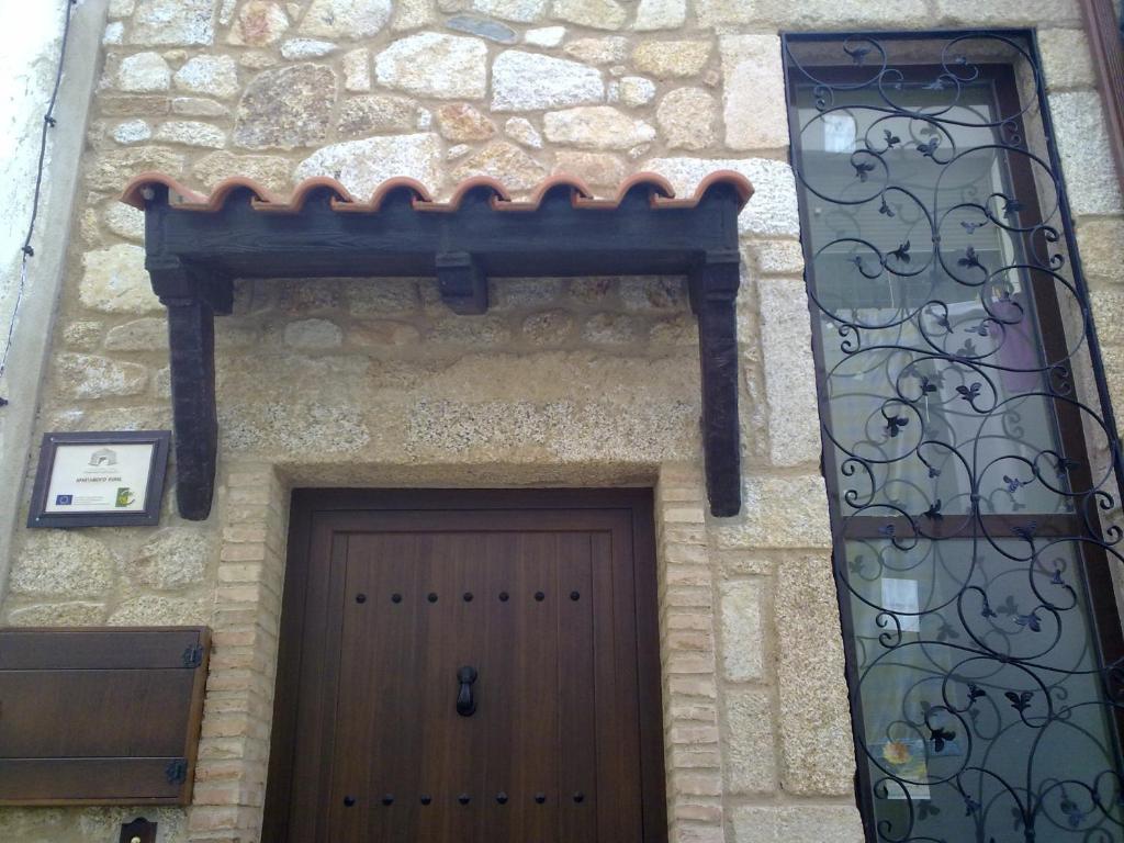 a stone building with a wooden door and a gate at La Casa del Telar in Valverde del Fresno