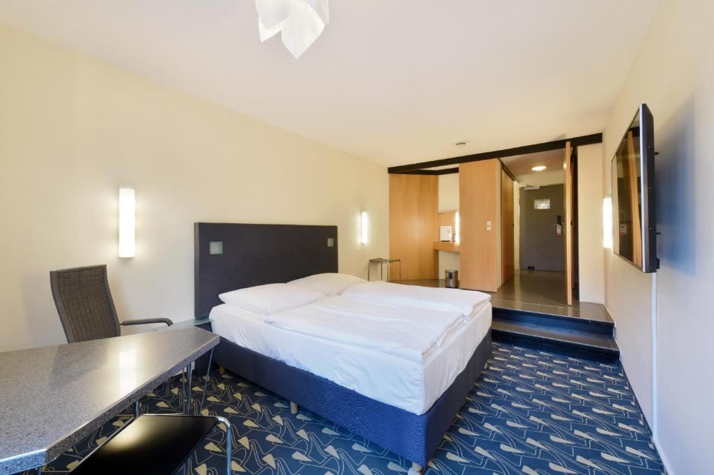 a hotel room with a large bed and a desk at Hotel Wiehberg - Self Check-In in Hannover