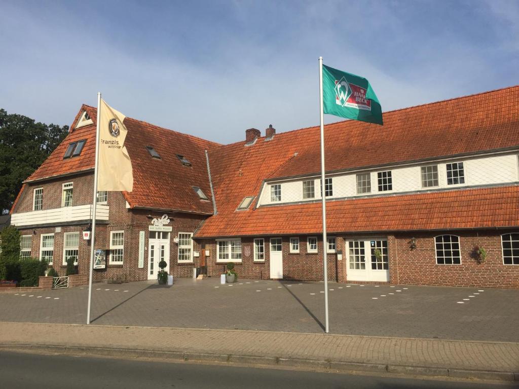 un edificio con dos banderas delante en Hotel Wuelfers Gasthaus, en Groß Ippener