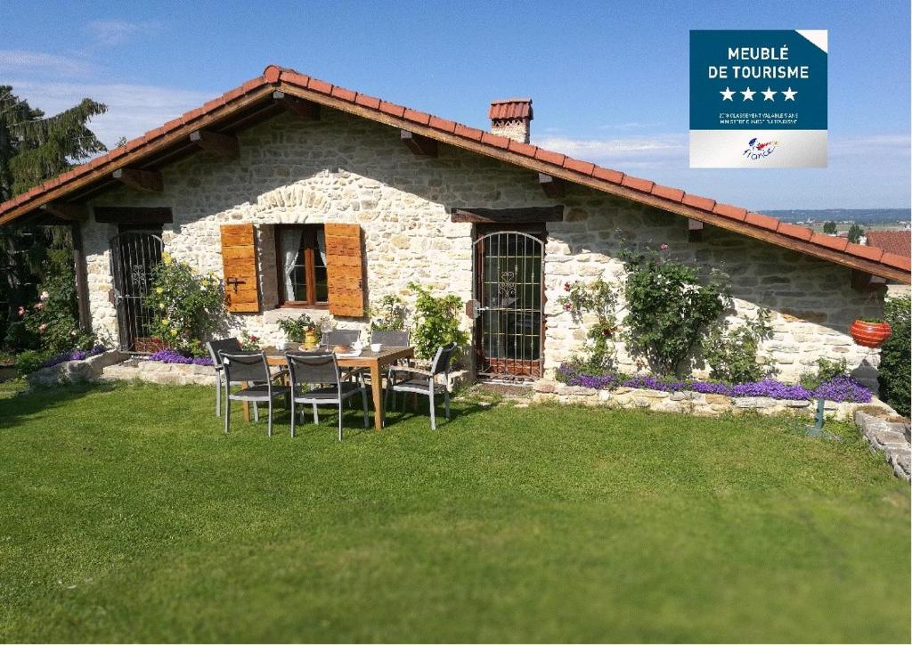 a stone house with a table and chairs in front of it at Le Grangeon 01 in Ambérieu-en-Bugey