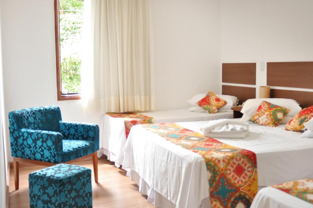 una habitación de hotel con 2 camas y una silla en Hotel Vitoria Marchi en Serra Negra
