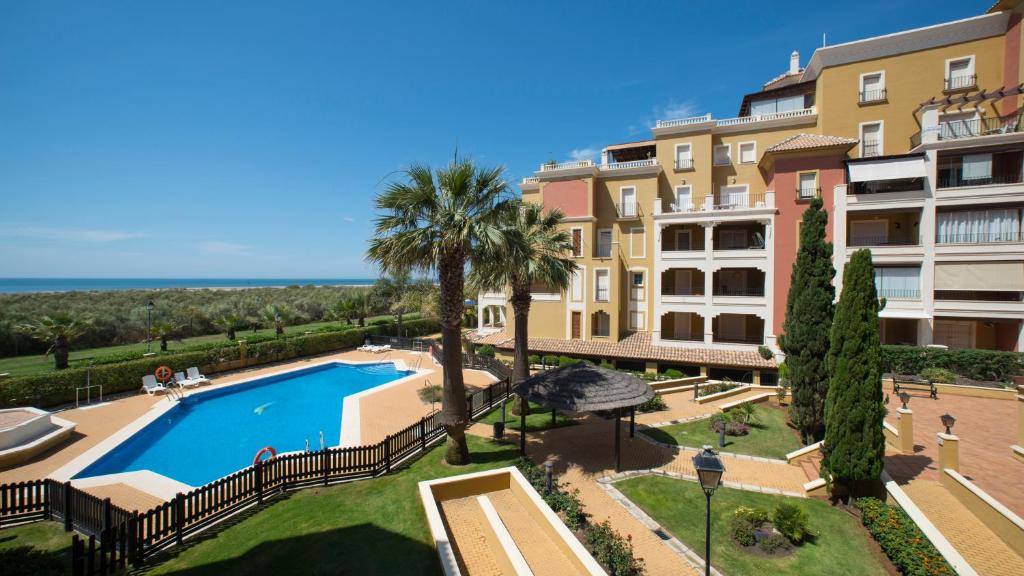 an apartment with a swimming pool in front of a building at Leo Rentals in Isla Canela