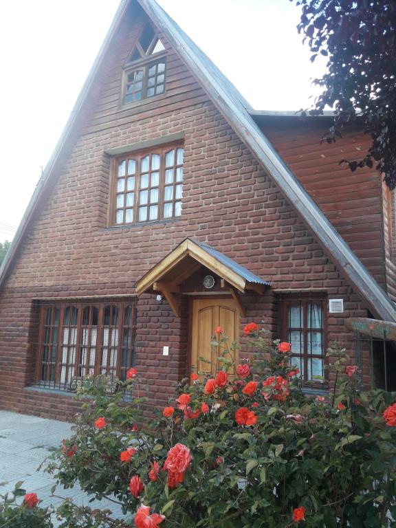 una casa de ladrillo con rosas rojas delante de ella en Freecis, en Esquel
