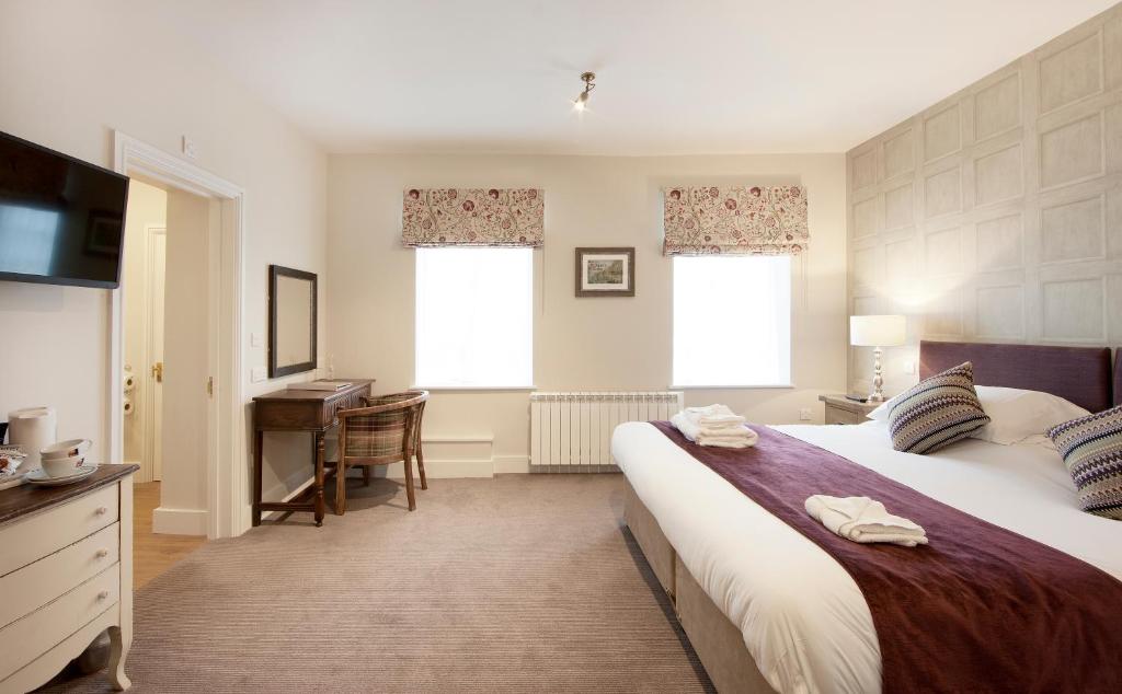 a bedroom with a bed and a desk and a television at The Talbot Hotel in Ledbury