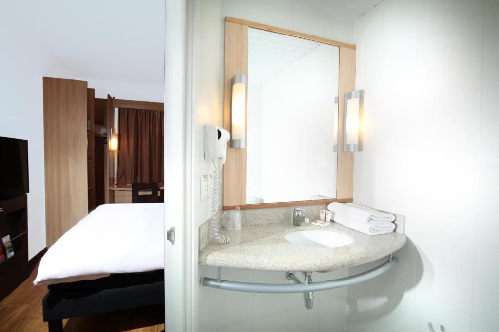 a bathroom with a sink and a bed at ibis Santiago Providencia in Santiago