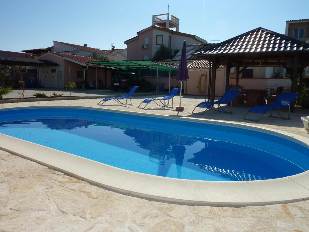 einen großen blauen Pool mit Stühlen und Tischen in der Unterkunft Queen beach Apartments - private pool - Sabunike III in Privlaka