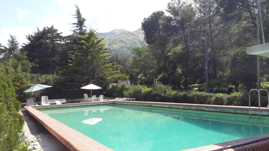 a swimming pool with chairs and umbrellas in a yard at Hotel Zapata in La Cumbre