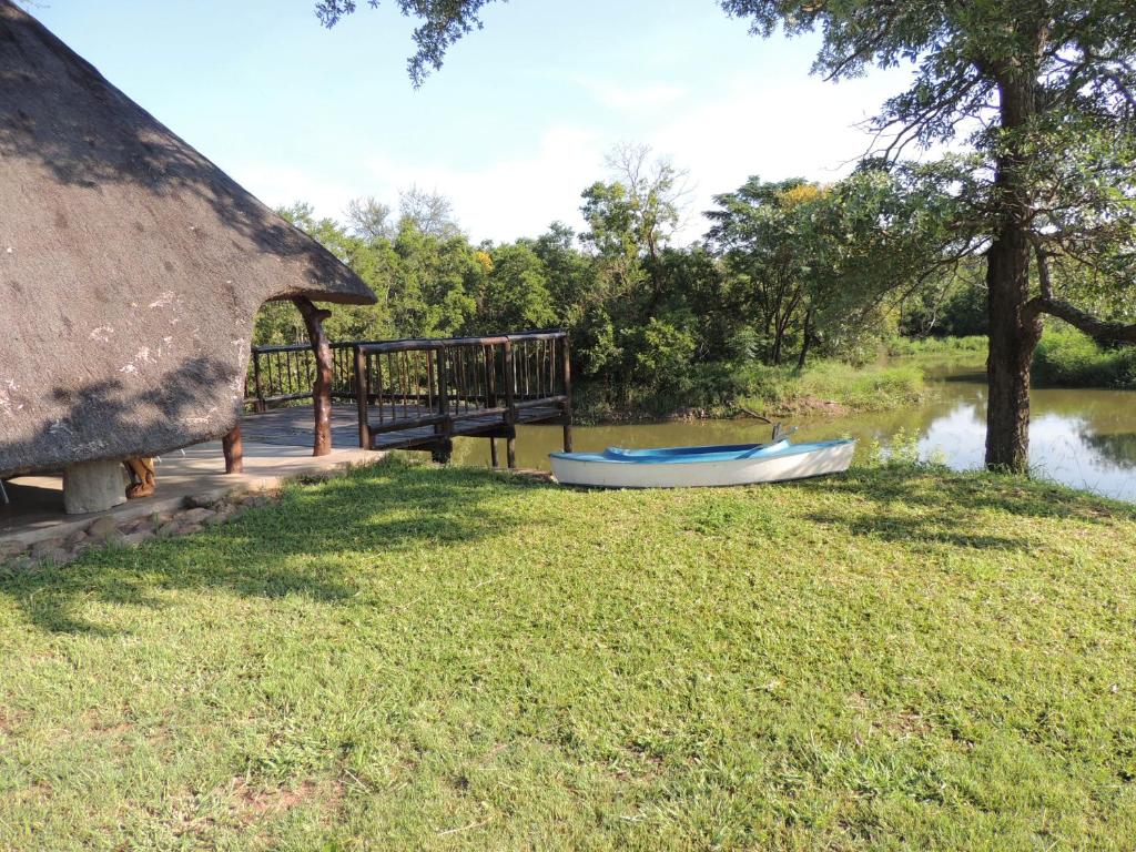 a boat sitting on the grass next to a hut at Karibu River Retreat in Marble Hall