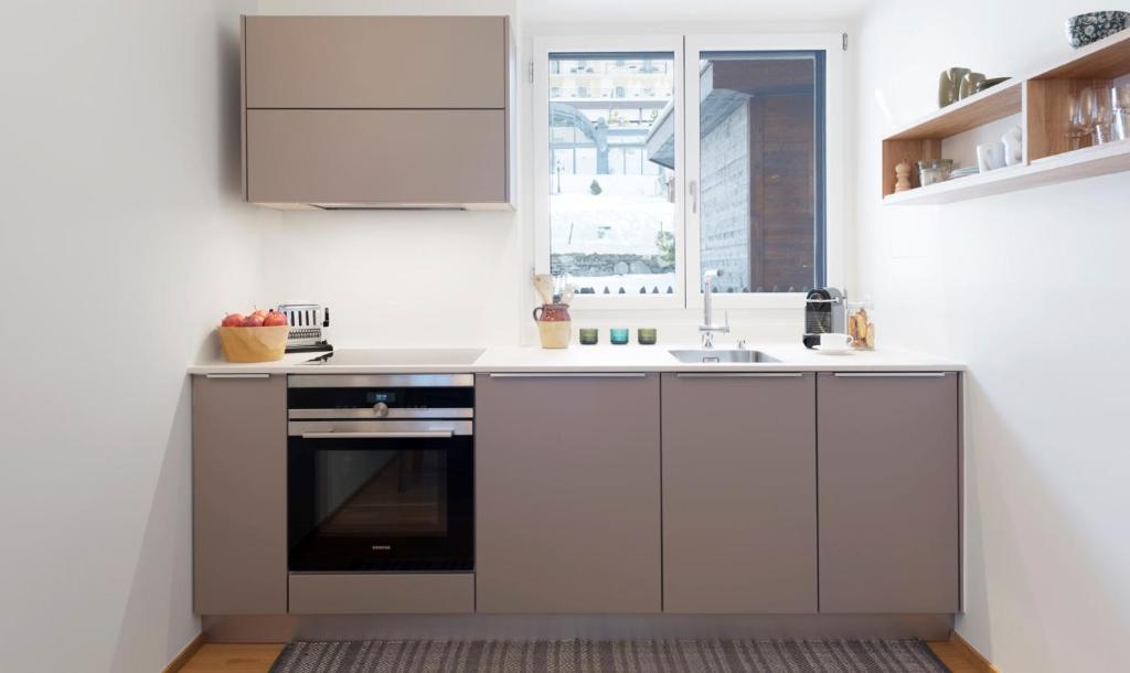 a white kitchen with a sink and a window at Haus-Ascot-Zermatt in Zermatt