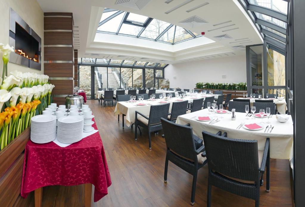 a dining room with white tables and black chairs at Hotel Dvorana in Karlovy Vary