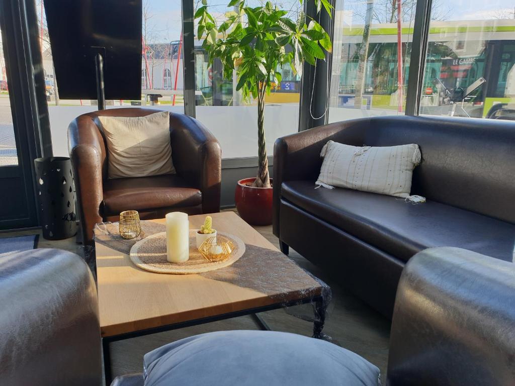 a living room with couches and a table and a chair at Hôtel de la Gare - Restaurant Bistro Quai in La Roche-sur-Yon