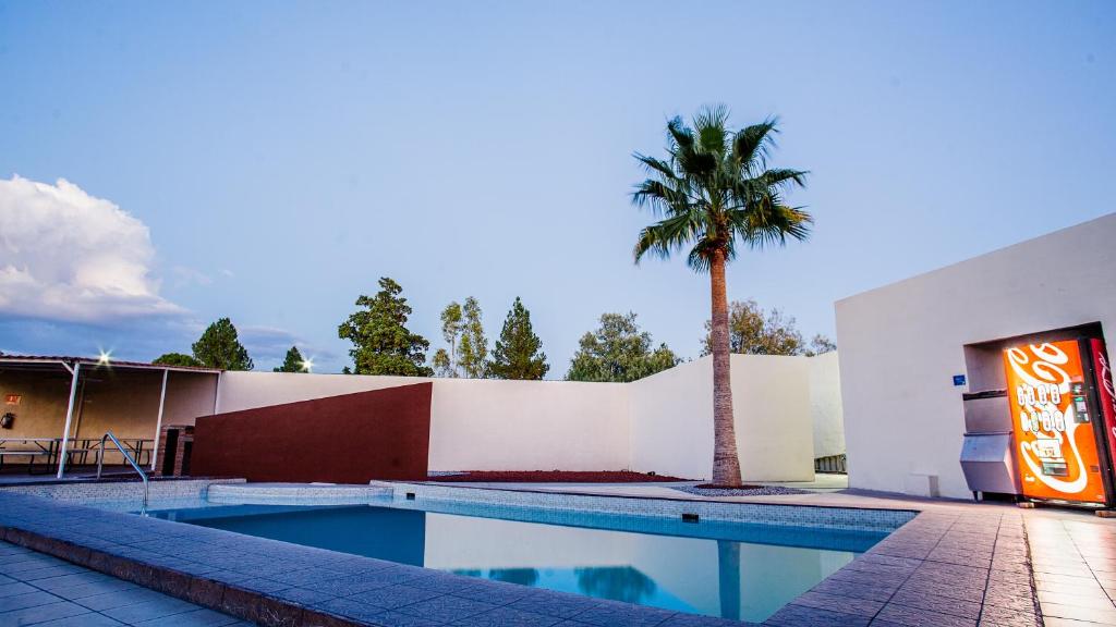 un edificio con una piscina y una palmera en American Inn Hotel & Suites Delicias en Delicias