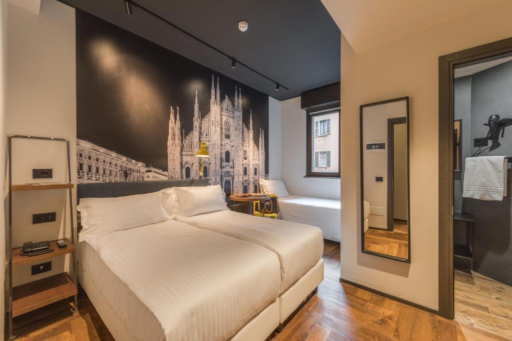 una camera con un grande letto bianco e un bagno di Hotel Roxy a Milano