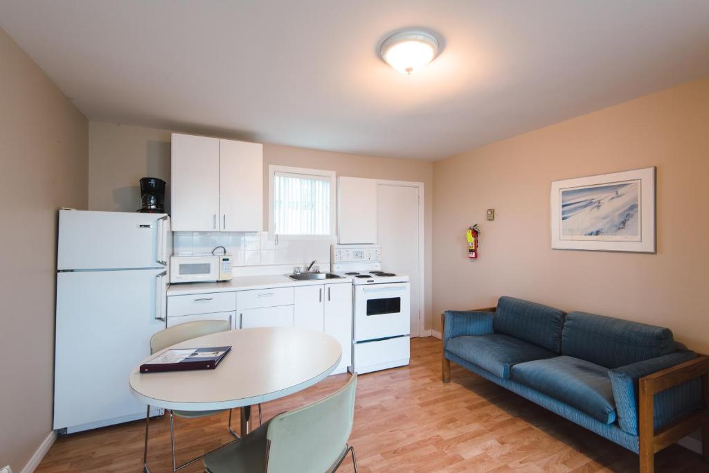 a kitchen with a table and a blue couch in a room at Auberge le Parasol in Saguenay