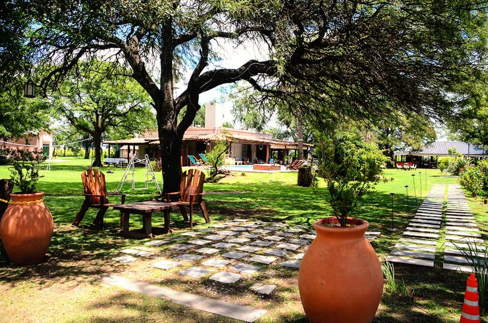 a garden with two large vases and a table and a tree at La Isolina Club de Campo in Villa María