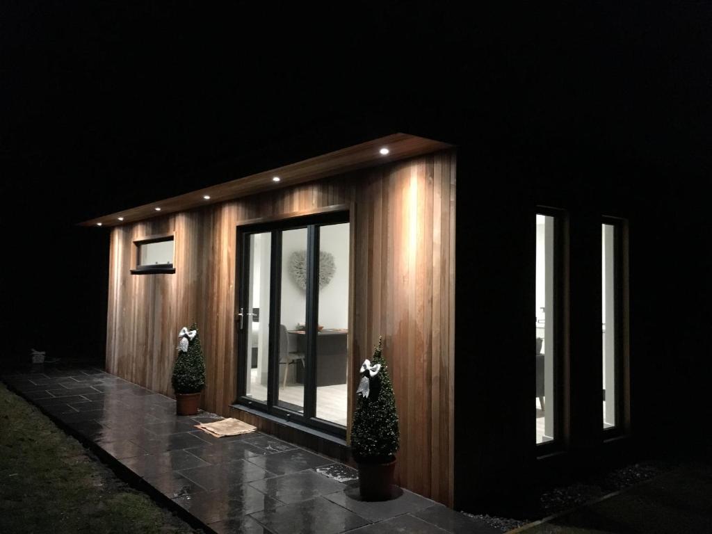 a small wooden house with two potted trees in front of it at Parkknott Retreat Luxury Lodge with Private Hot Tub in Askam in Furness