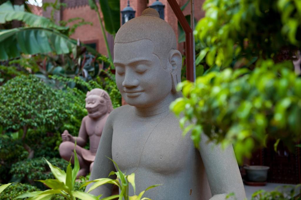 a statue of a man and a monkey in a garden at Okay Guesthouse Siem Reap in Siem Reap