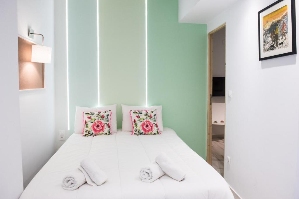 a bedroom with a white bed with pink pillows at Tulip #Colony city center in Thessaloniki