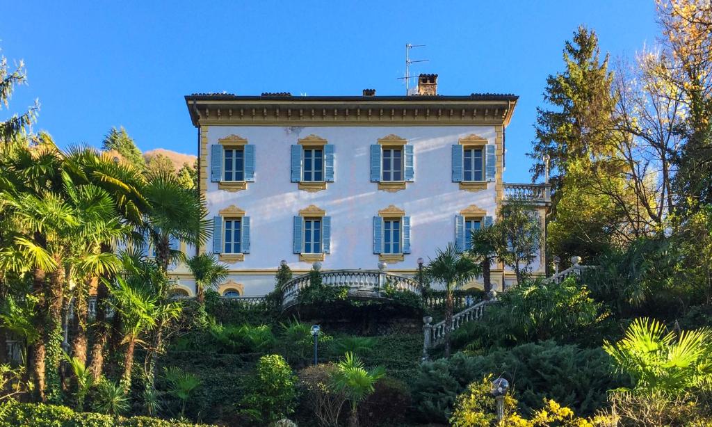 uma grande casa branca numa colina com árvores em B&B Villa Costanza em Blevio