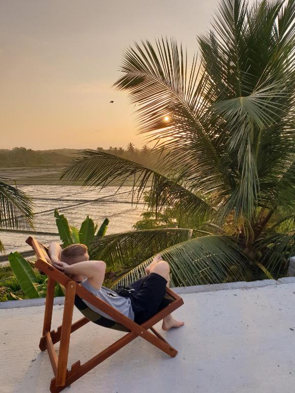 a man laying in a chair on a beach at Rice Field View Home Stay in Tangalle