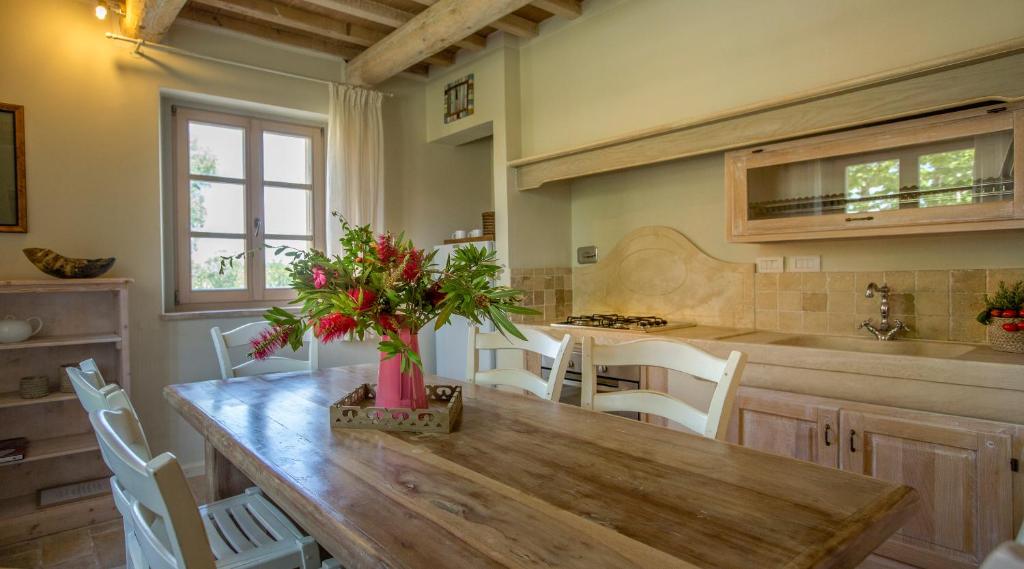 cocina con mesa de madera y sillas blancas en Residence La Beccanina, en Scarlino