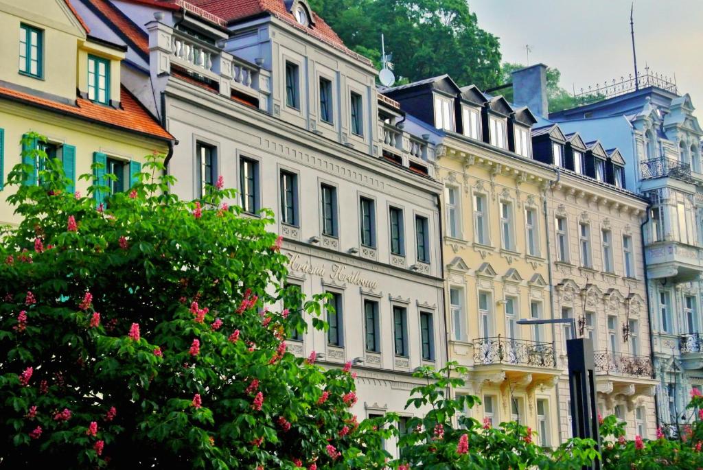 a group of buildings with a tree in the foreground at Hotel Renesance Krasna Kralovna in Karlovy Vary