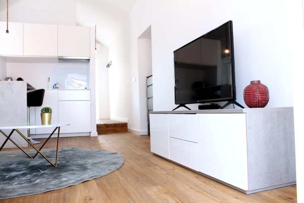 a living room with a flat screen tv on a white cabinet at Miradouro's Loft in Setúbal