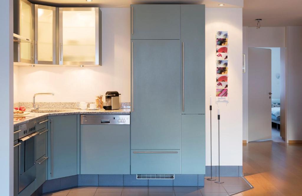 a kitchen with blue cabinets and a refrigerator at Haus-Ascot-Zermatt in Zermatt