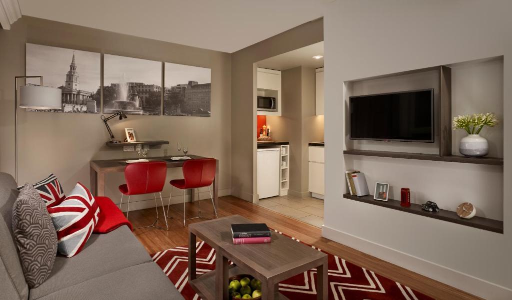 a living room with a couch and a table and a kitchen at Citadines Trafalgar Square in London