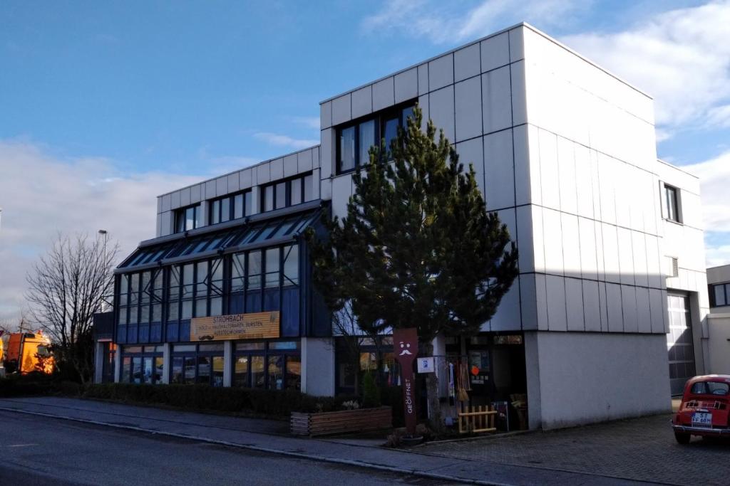 a white building with a tree in front of it at Atelierhaus Budget Hotel in Filderstadt