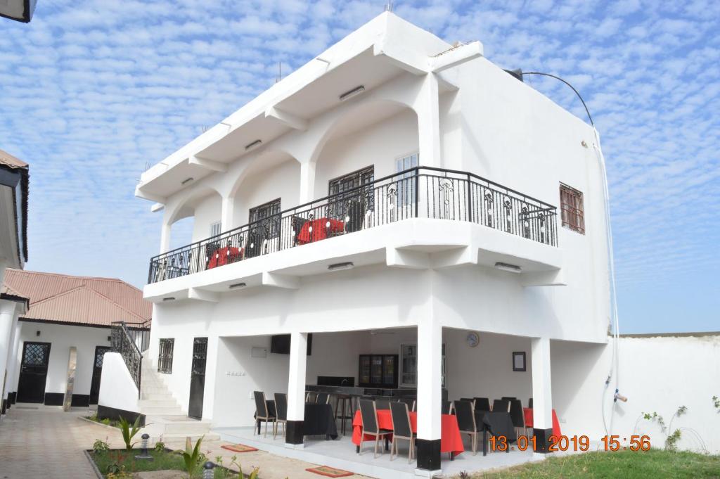 a white house with a balcony and red chairs at Sukuta Nema Guest House in Bathurst