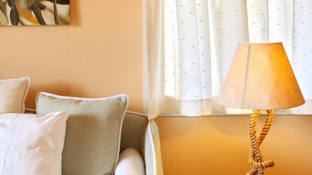una lámpara junto a una cama con ventana en Elaia Boutique Apartments, en Gáios