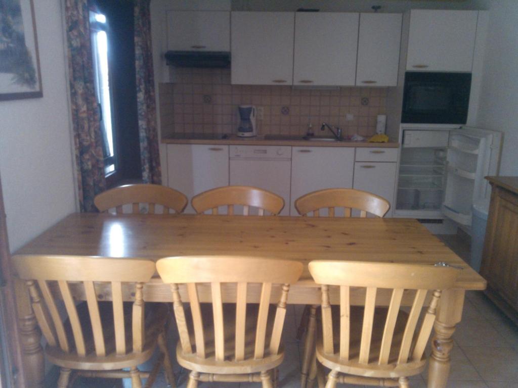 cocina con mesa de madera y sillas en Vakantiewoning De Haan, en De Haan