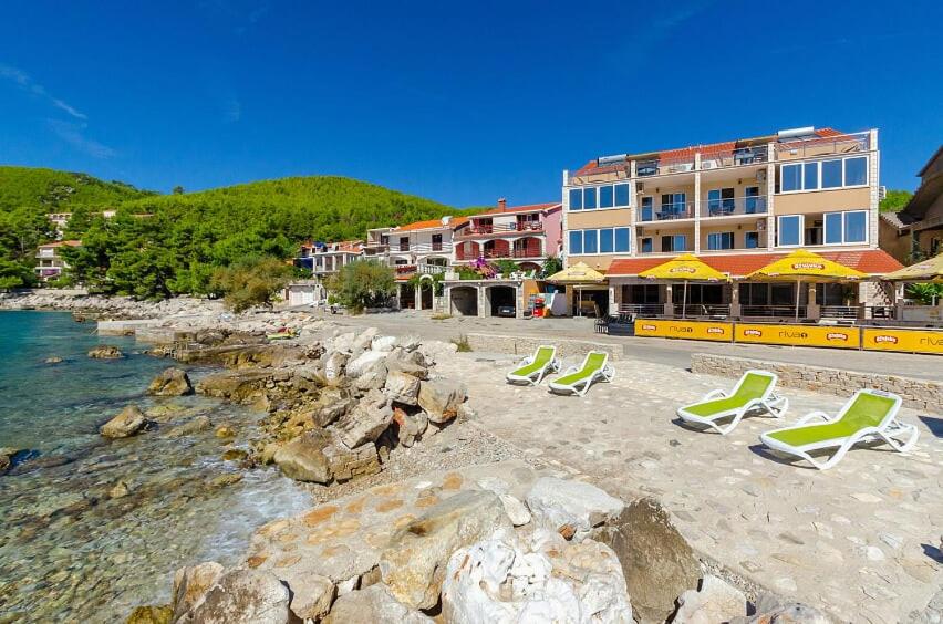 a beach with lounge chairs and a hotel at Riva1 Apartments and Rooms in Prizba