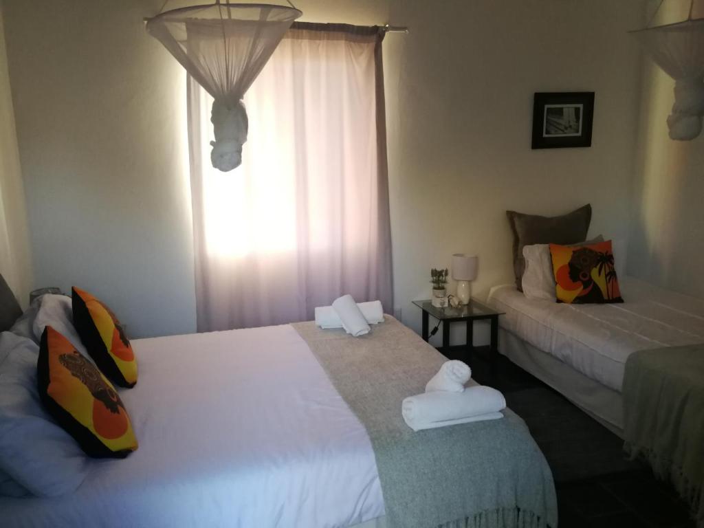 1 dormitorio con 2 camas y ventana en Kamelruhe Guest House & Camping, en Gochas