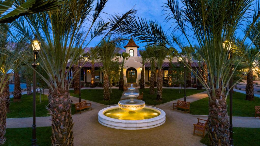 a large fountain in front of a building with palm trees at The Ranch At Death Valley in Indian Village