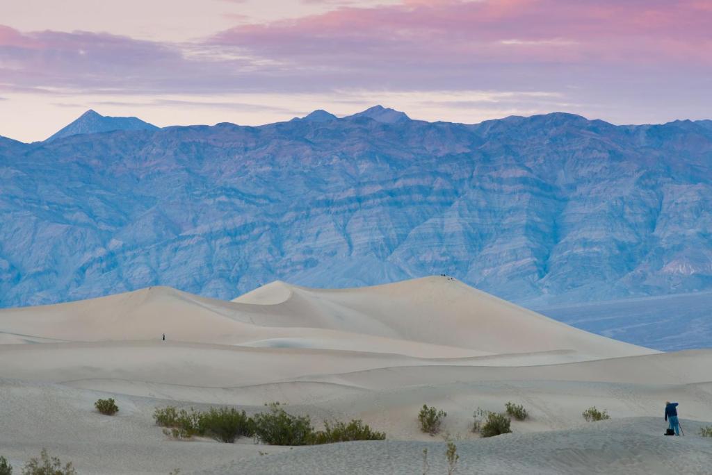 a person standing on a sand dune in front of mountains at The Ranch At Death Valley in Indian Village
