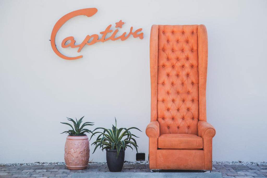Captiva Beach Resort (open private beach access) في ساراسوتا: كرسي برتقالي ونباتات الفخار أمام الجدار