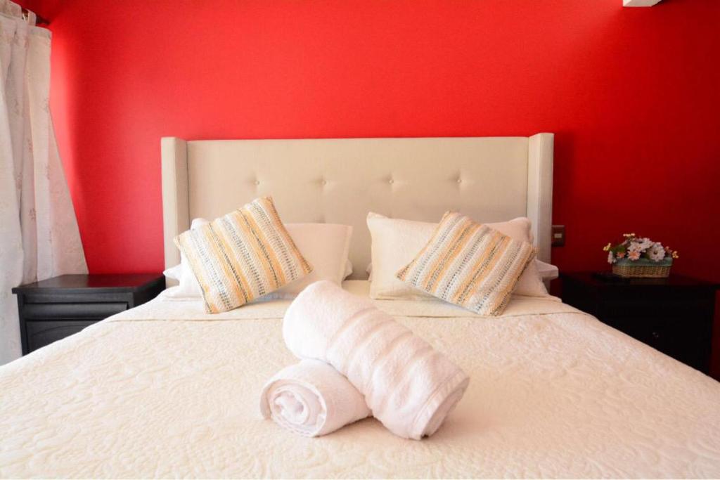 1 dormitorio con cama blanca y pared roja en Complejo Molco Sur con Piscina, en Pucón