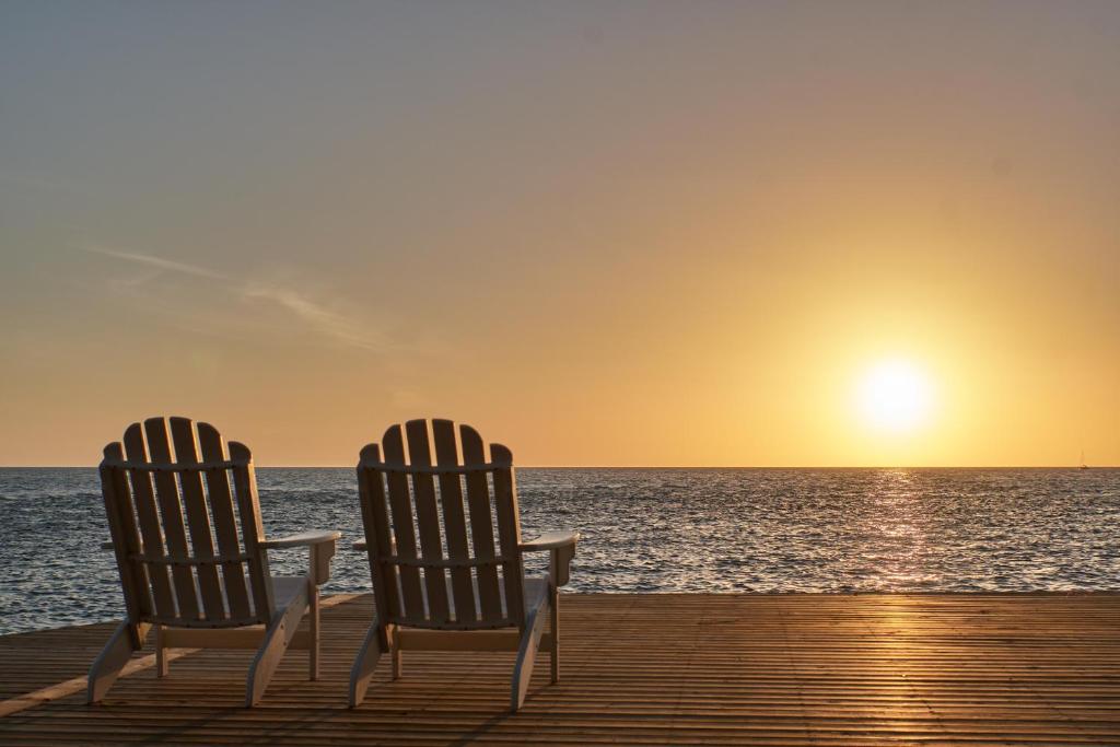 two chairs sitting on a dock watching the sunset at Isla Bella Beach Resort & Spa - Florida Keys in Marathon